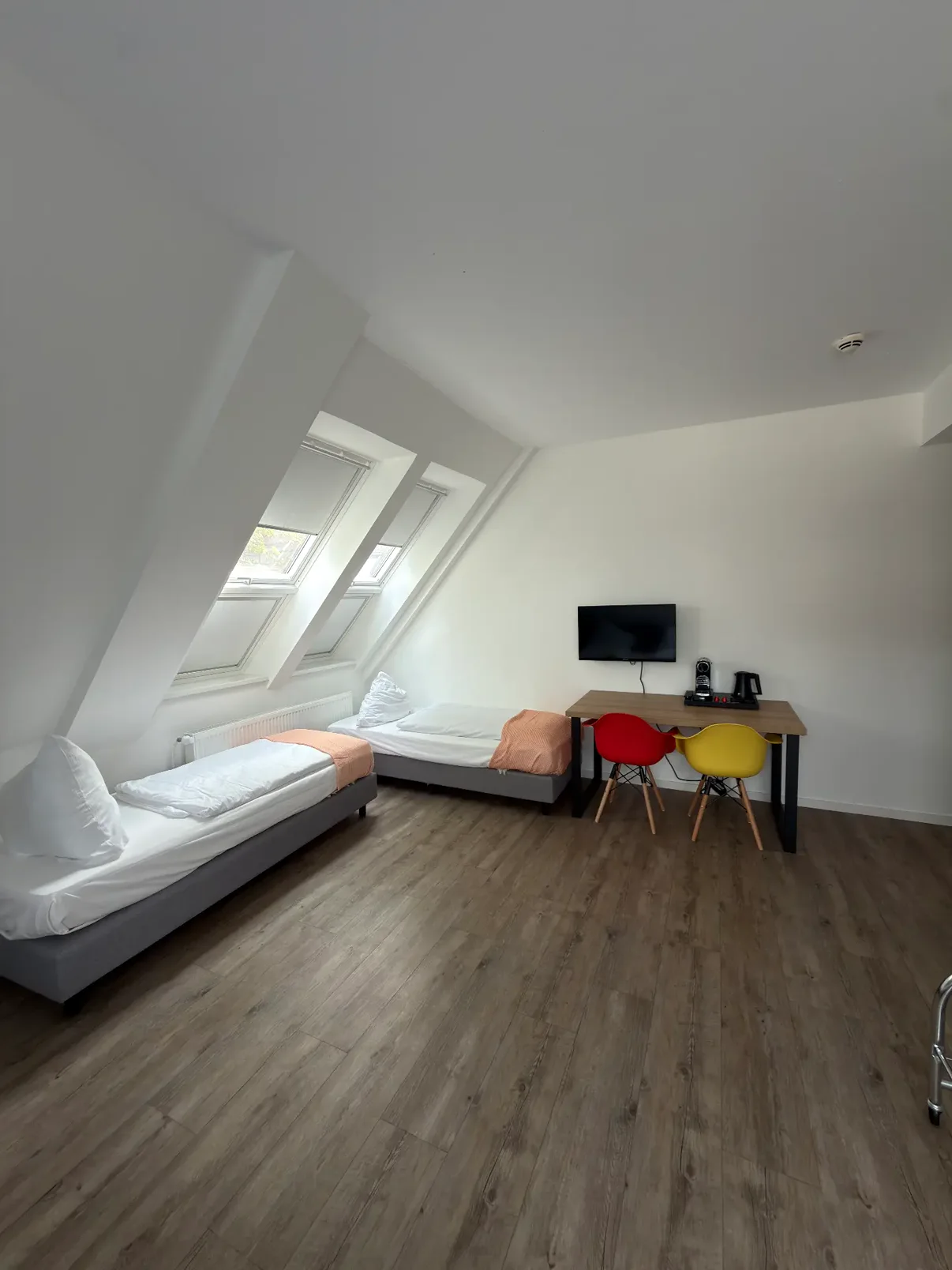 Helles Zimmer mit zwei Einzelbetten, Dachfenstern und Arbeitstisch