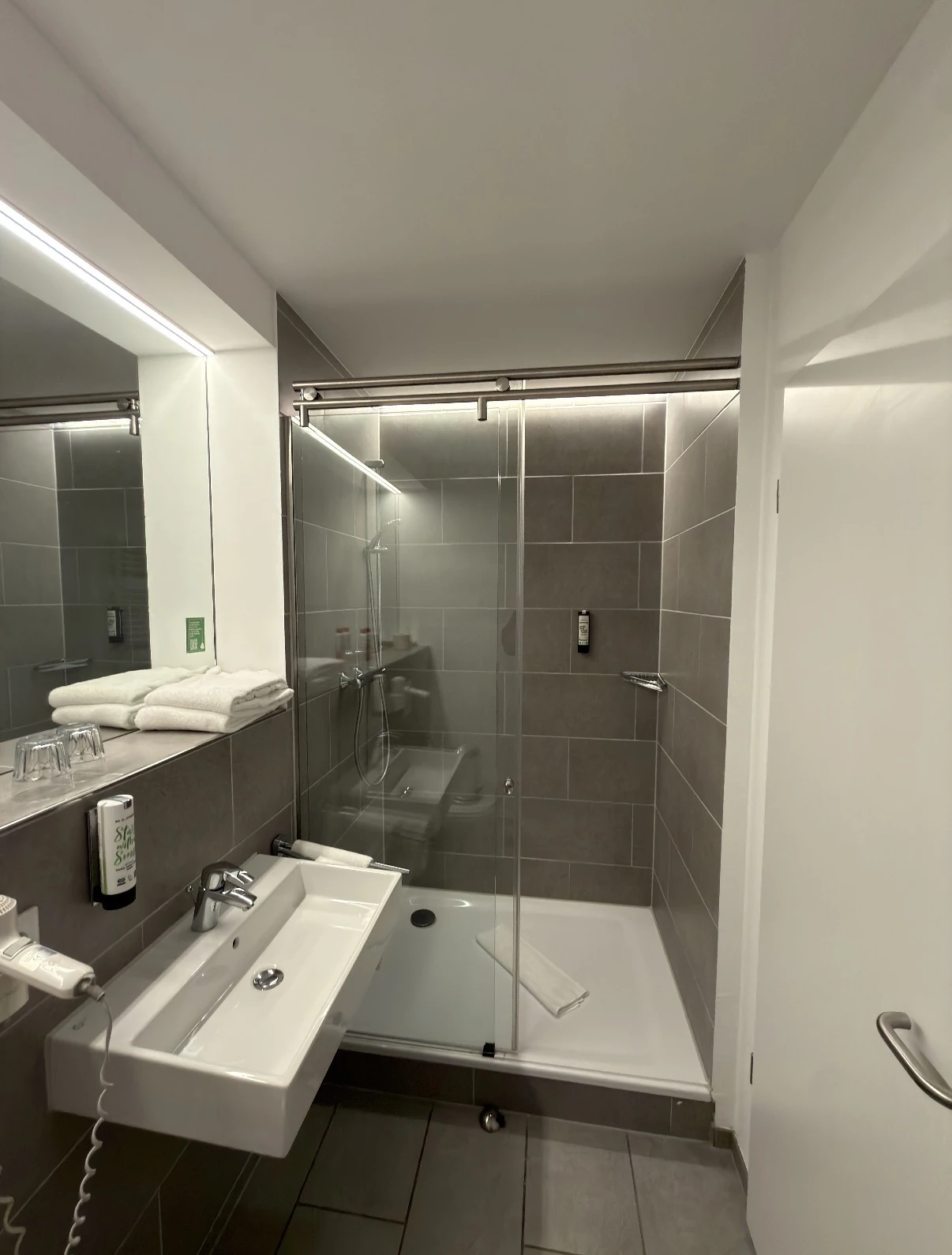 Moderne Glasdusche mit grauen Fliesen