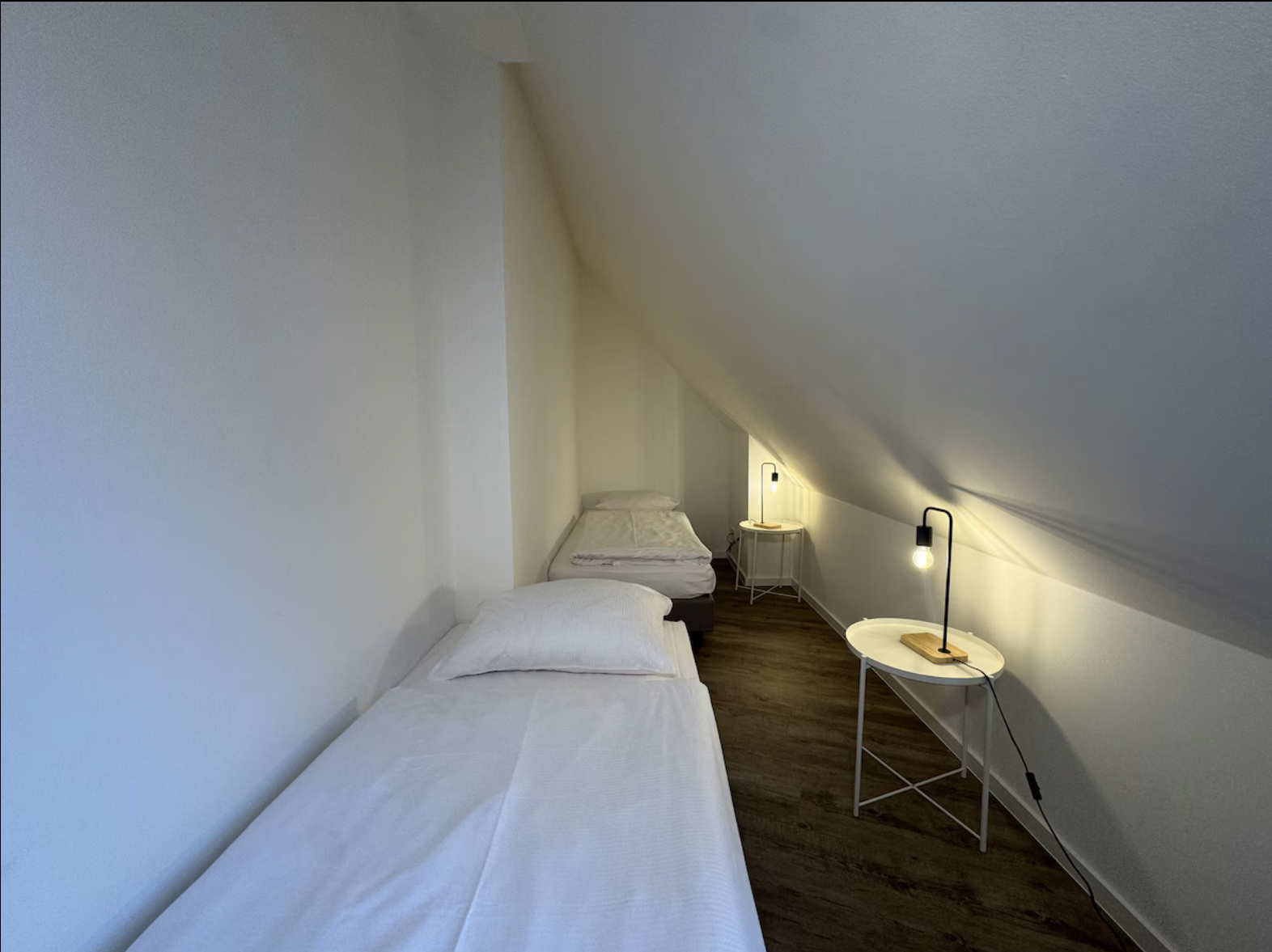 Doppelbett mit weißer Bettwäsche und Leselampen