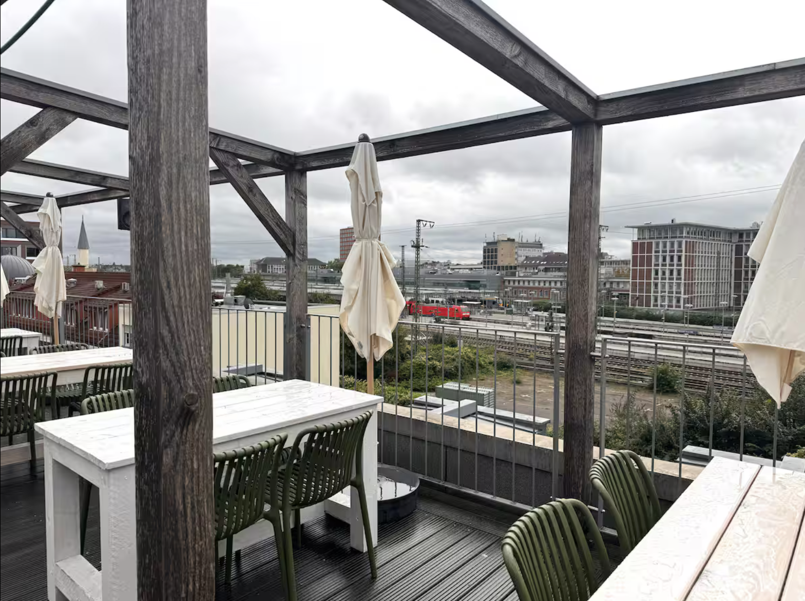Überdachte Terrasse mit Holzmöbeln und Blick auf die Gleise